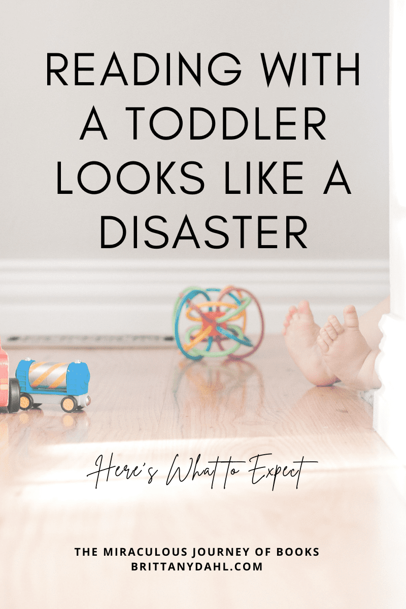 Reading with a toddler looks like a disaster: here's what to expect. Image of toddler hiding behing a wall with their feet sticking out. Toys strewn across the floor.