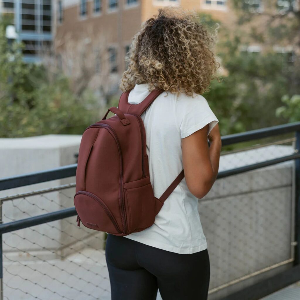 Image of woman carrying raising-colored Lite Backpack from Parker Baby Co. Great option for baby reading gifts.