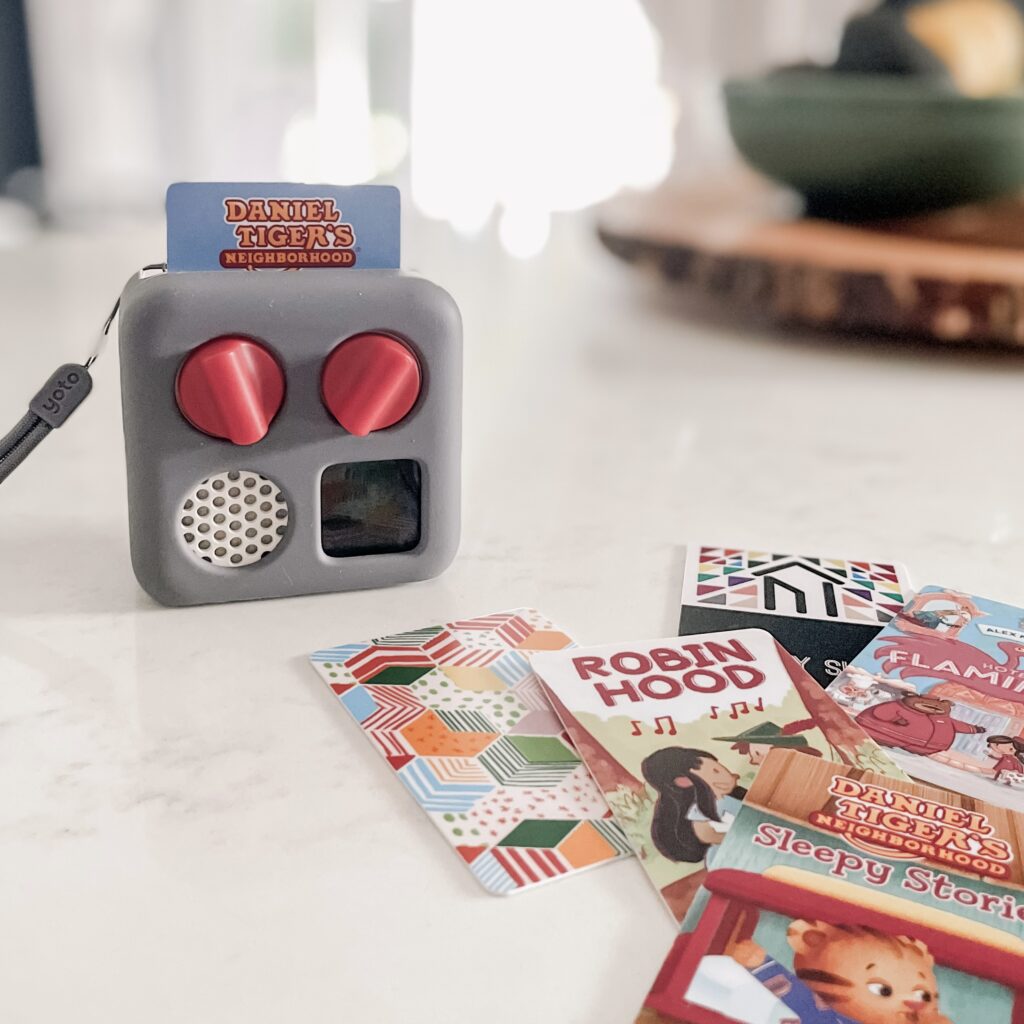 Image of Yoto Mini and several Yoto Storycards -- Daniel Tiger, Robinhood, and Hotel Flamingo.