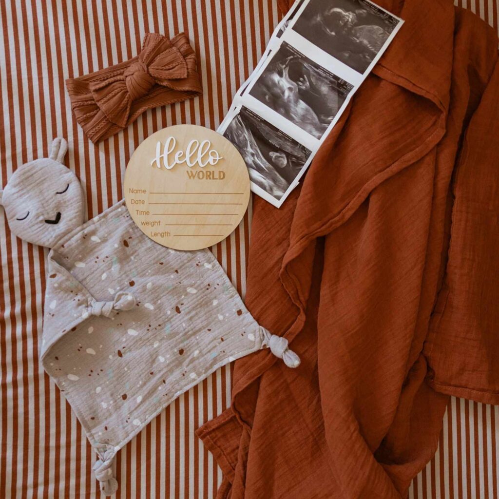 Image of ParkerBabyCo's alpaca lovey. Flatlay image that looks like a birth announcement -- lovey, headband, blanket, and sonogram images.